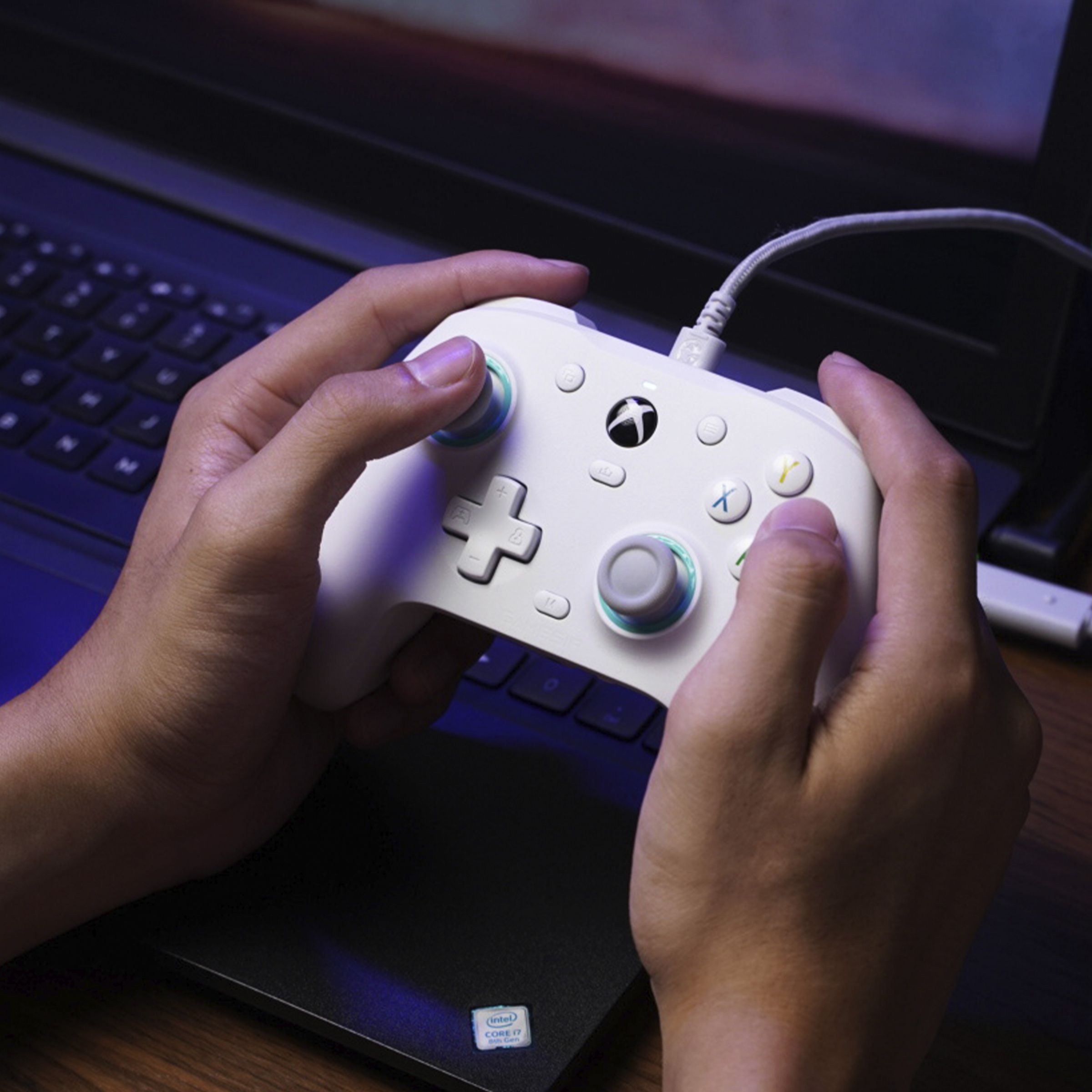 A pair of hands playing a white GameSir G7 SE controller on a laptop.