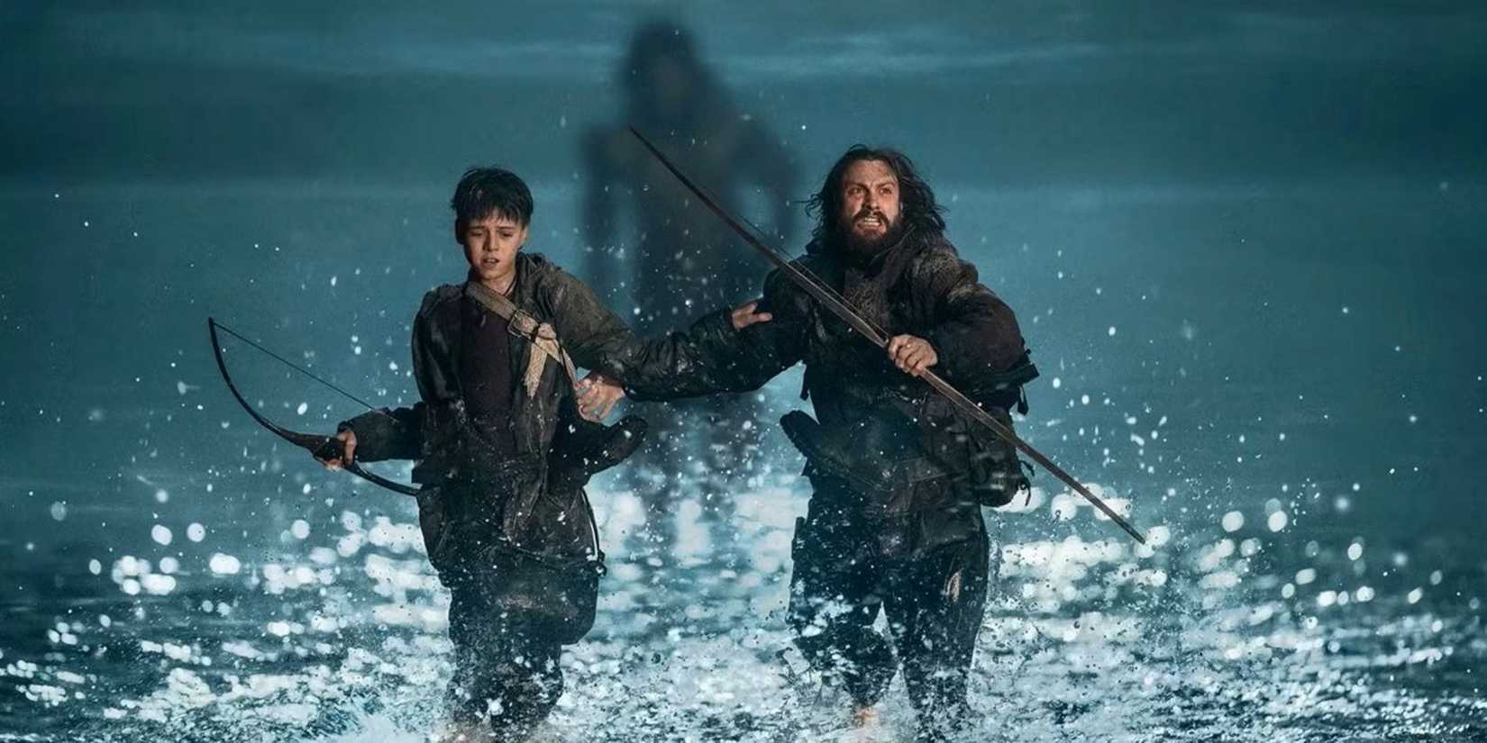 A father and son are pursued through a narrow causeway by a zombie in a scene from 28 Years Later