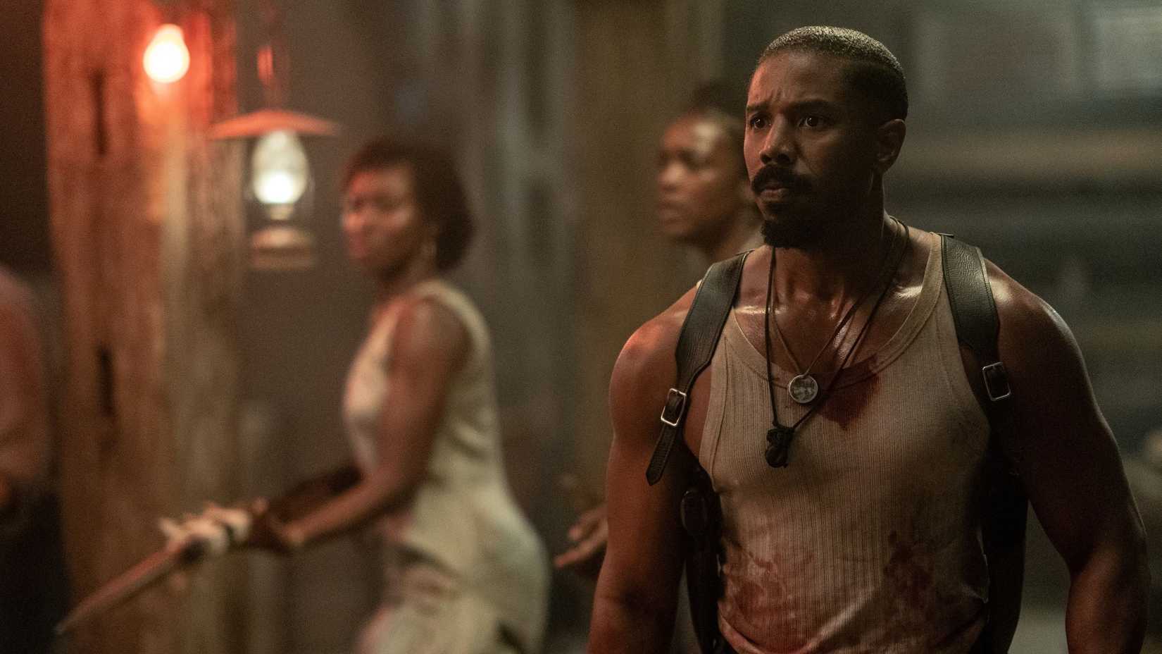 Michael B. Jordan, sweaty and in a blood-spattered sleeveless T-shirt, looks worried and stricken in Ryan Coogler’s Sinners
